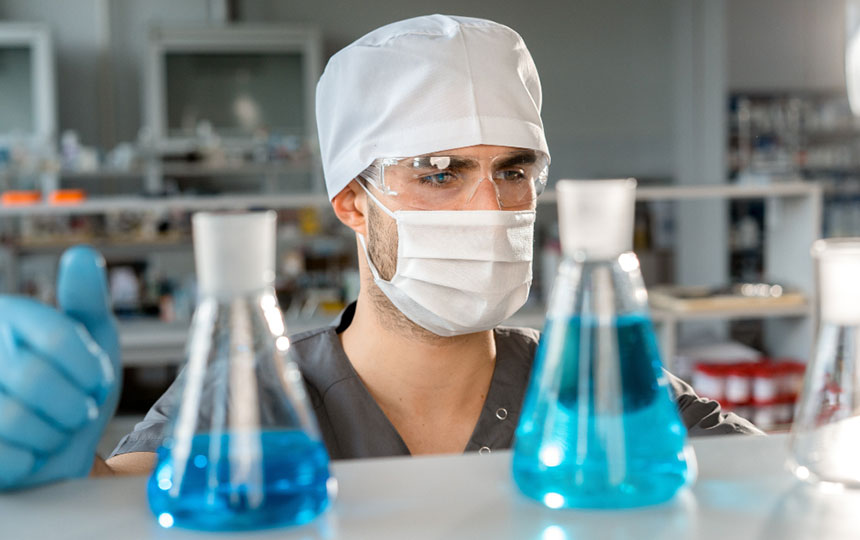 lab tech observing liquids in Erlenmeyer flasks